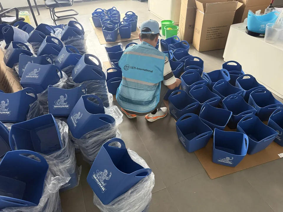 床に広げた青い布製収納袋のロットを確認するSSTIの検査員
